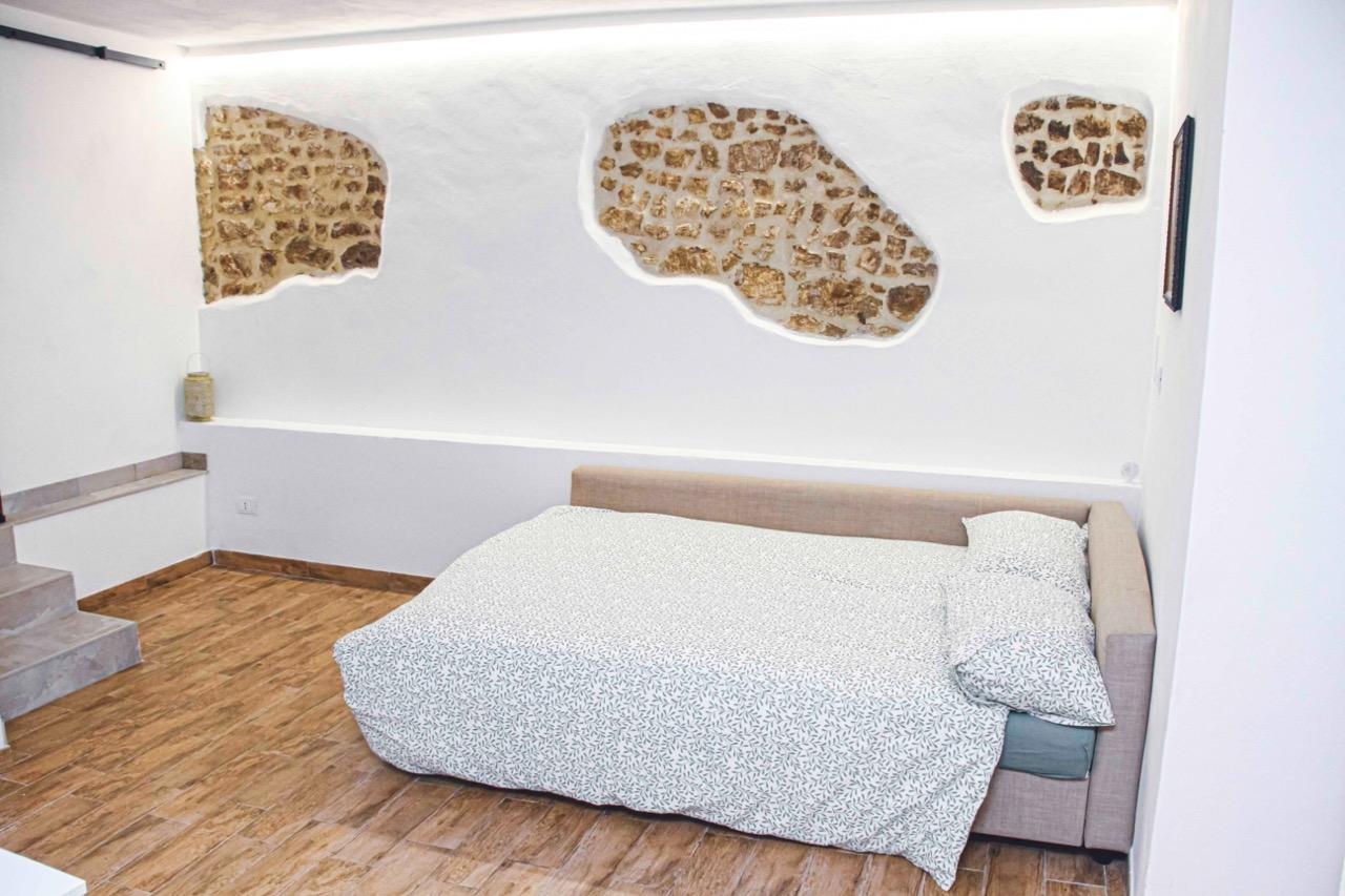 Dettaglio divano letto e parete in pietra